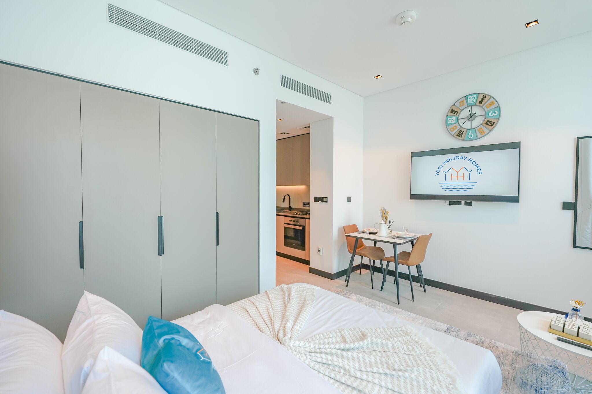 Una habitación de hotel moderna con una cama, un escritorio y una kitchenette al fondo.