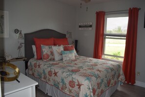 A bedroom with a bed, a nightstand, a lamp, and a window with curtains.
