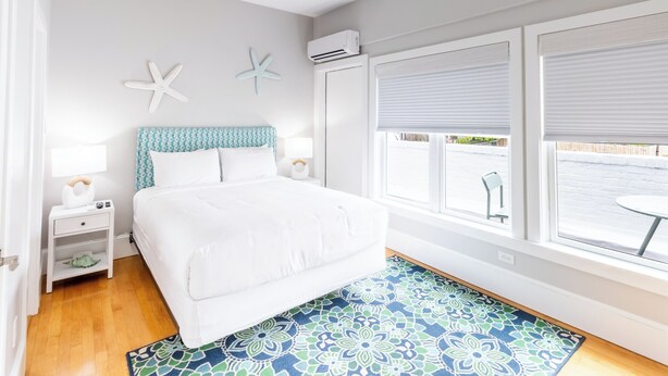A bedroom with a bed, nightstands, a window with blinds, and a starfish decoration on the wall.
