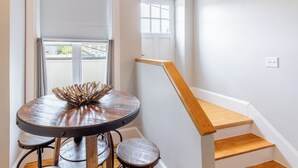A staircase with wooden steps and a wooden handrail, leading to a landing with a round table and two chairs.