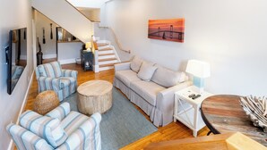 A modern living room with a sofa, chairs, a coffee table, and a staircase.