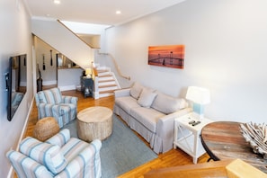 A modern living room with a sofa, chairs, a coffee table, and a staircase.