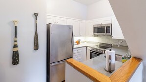 A modern kitchen with white cabinets, stainless steel appliances, and a wooden countertop.