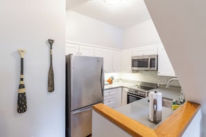 A modern kitchen with white cabinets, stainless steel appliances, and a wooden countertop. - Two Level Condo with all the Essentials, Thames St (Newport)