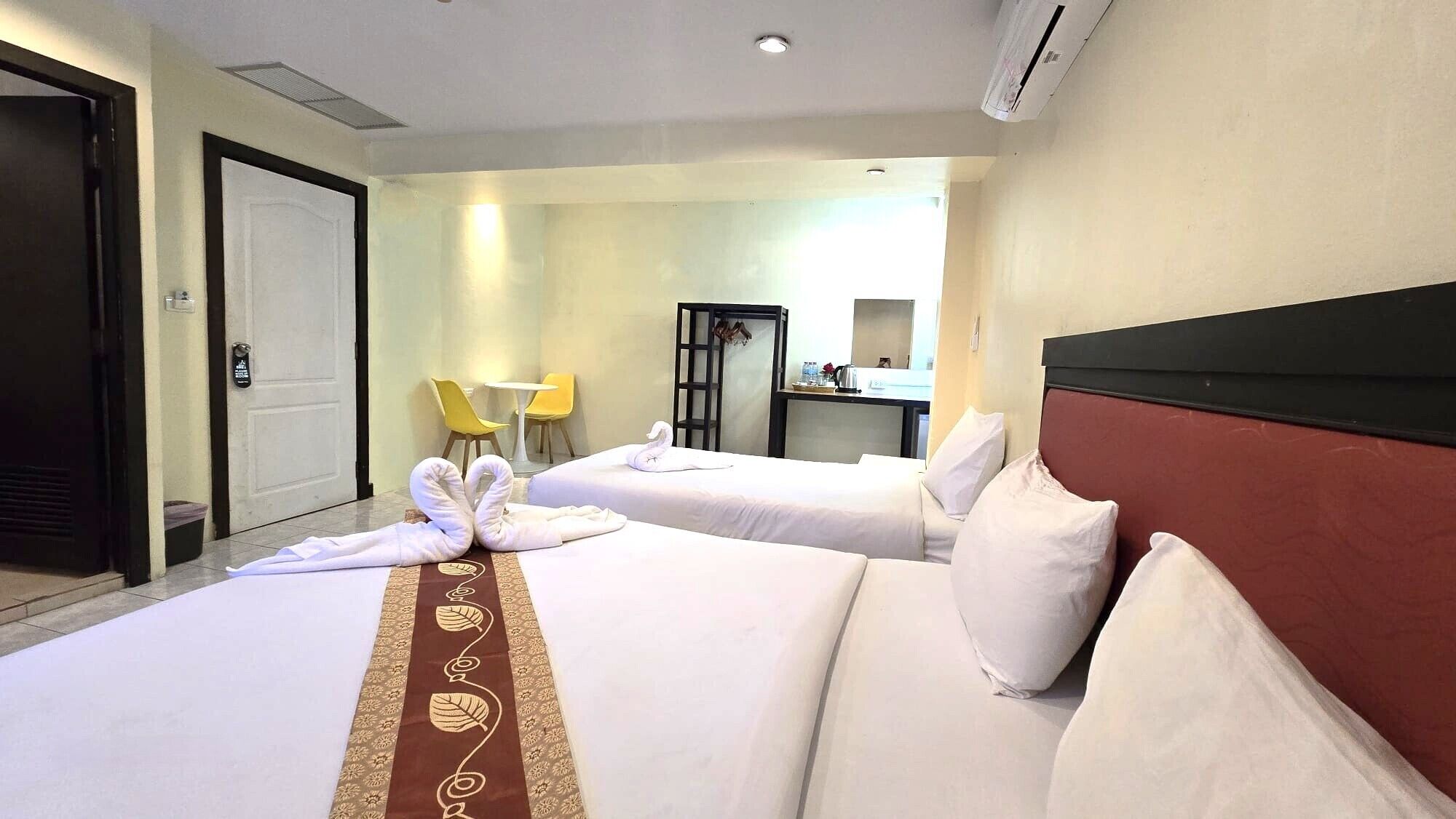 Habitación de hotel con dos camas, un escritorio, una silla y un espejo.
