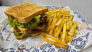 A meal of toasted bread, lettuce, and fries is served on a decorative paper.