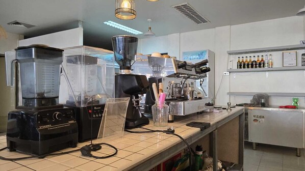 Una cocina industrial con una máquina de café, una licuadora y un dispensador de café.