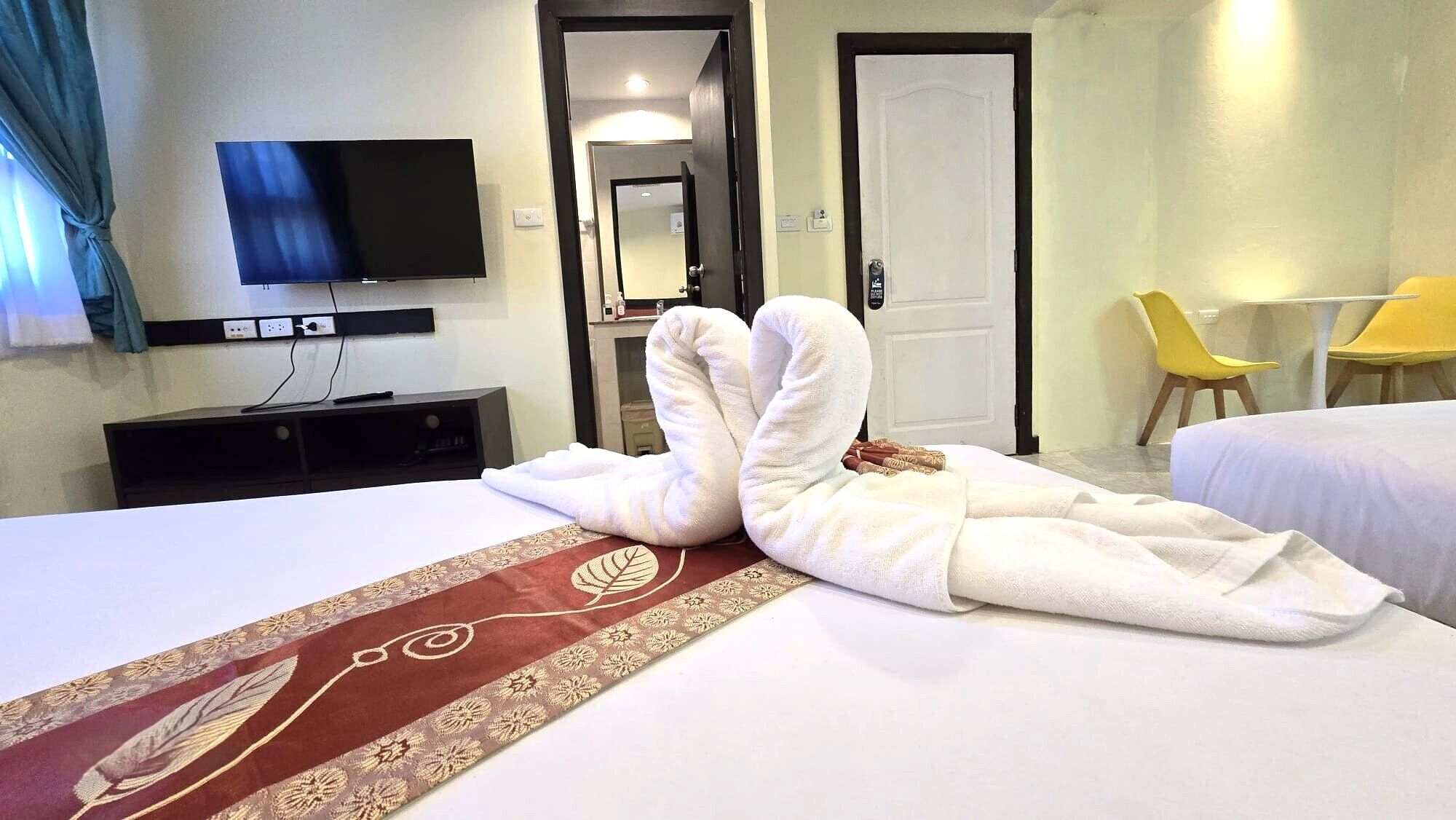 A hotel room with a bed, a TV, a desk, and a chair.