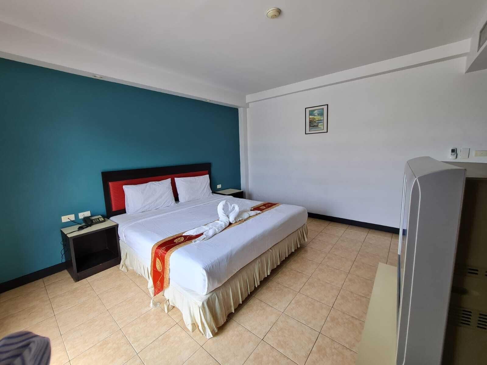 A hotel room with a bed, a nightstand, a TV, and a wall-mounted picture.