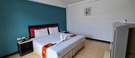 A hotel room with a bed, a nightstand, a TV, and a wall-mounted picture.