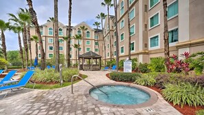A hotel courtyard with a swimming pool, lounge chairs, palm trees, and a gazebo. - Suites at Lake Buena Vista close Disney Spring (Orlando)