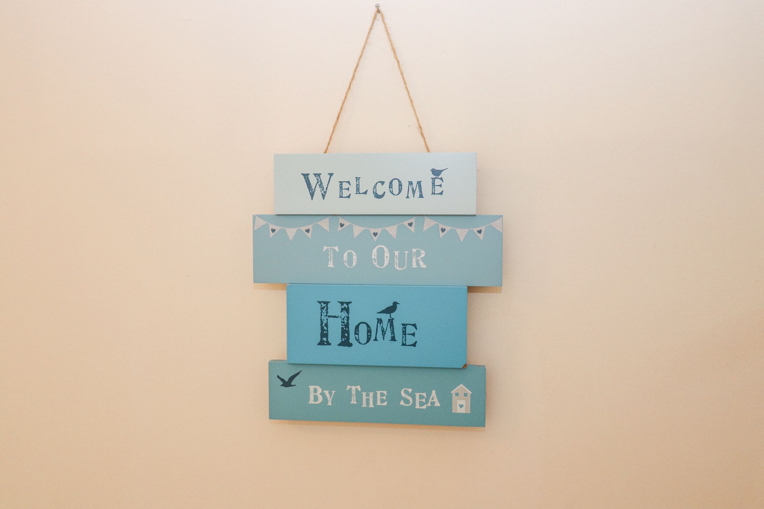 Un letrero de bienvenida con el texto 'Bienvenido a nuestro hogar junto al mar'.