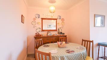 A dining area with a round table covered in a polka dot tablecloth, surrounded by wooden chairs.