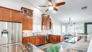 A modern kitchen with wooden cabinets, stainless steel appliances, and a granite countertop.