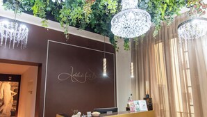 A reception desk with a dark wood finish, a chandelier, and a sign that reads "Adelaide Suite Dreams." - Adelaide Suite Dreams (Rome)