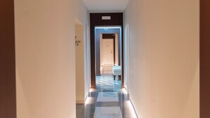 A modern hotel corridor with a reflective floor, a well-lit reception area, and a visible door labeled "HOTEL." - Adelaide Suite Dreams (Rome)