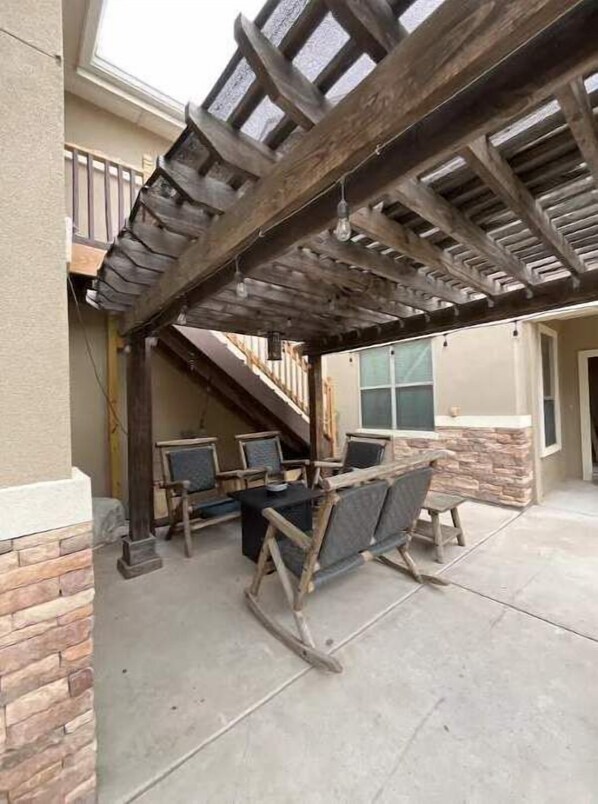 Relax in a shaded outdoor space beneath a rustic pergola, perfect for dining or socializing.