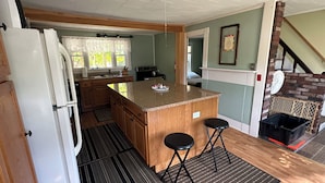 A compact kitchen with a central island, wooden cabinets, a refrigerator, and a sink.
