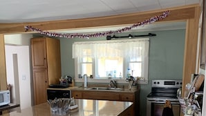 A kitchen with wooden cabinets, a granite countertop, a stainless steel oven, and a window with a curtain.