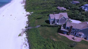 An aerial view of a coastal property with a large house, a beach, and a staircase leading to the beach. - 8 The Gridiron (Sandwich)