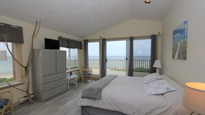 A bedroom with a bed, a TV, a chair, a desk, and a balcony with a view of the sea. - 8 The Gridiron (Sandwich)