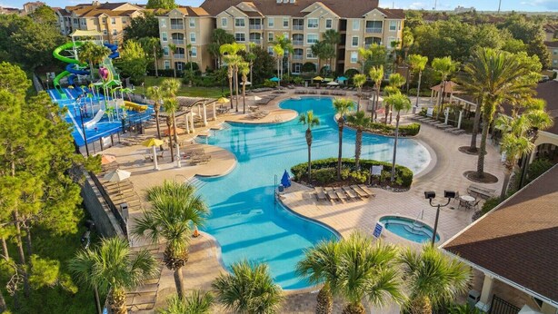 Un hotel con varias piscinas, un parque acuático y una zona ajardinada con palmeras.