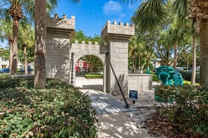 A gated entrance with a stone archway, surrounded by greenery and palm trees.