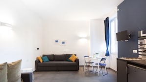 A compact living space with a sofa, a dining table, and a kitchenette. - Terrasse Manuela Apartment 1 (Napoli)
