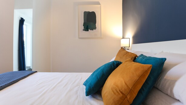 A hotel room with a bed, pillows, a framed artwork on the wall, and a nightstand with a lamp. - Terrasse Manuela Apartment 1 (Napoli)