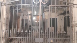A wrought iron gate with intricate designs, leading to a building with arched windows and a bell tower. - Terrasse Manuela Apartment 1 (Napoli)