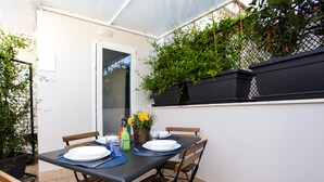 A dining table set for four with chairs, a window, and potted plants. - Terrasse Manuela Apartment 1 (Napoli)