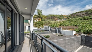A modern balcony with a view of a hillside garden and distant buildings. - Til Home by Homie in Funchal (Funchal)