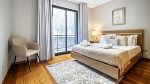 A modern hotel room with a large bed, a chair, a window with curtains, and a framed picture on the wall. - Til Home by Homie in Funchal (Funchal)