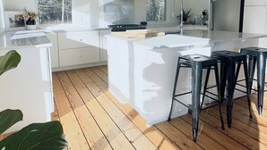 Eine moderne Küche mit weißen Schränken, einer Kochinsel und Holzboden.