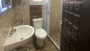 A bathroom with a sink, toilet, and shower. - Luxurious Modern Apartment (Madinaty)