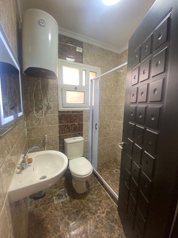 A bathroom with a sink, toilet, and shower. - Luxurious Modern Apartment (Madinaty)
