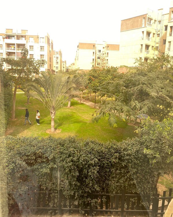 A residential area with a grassy park, trees, and a fence. - Luxurious Modern Apartment (Madinaty)