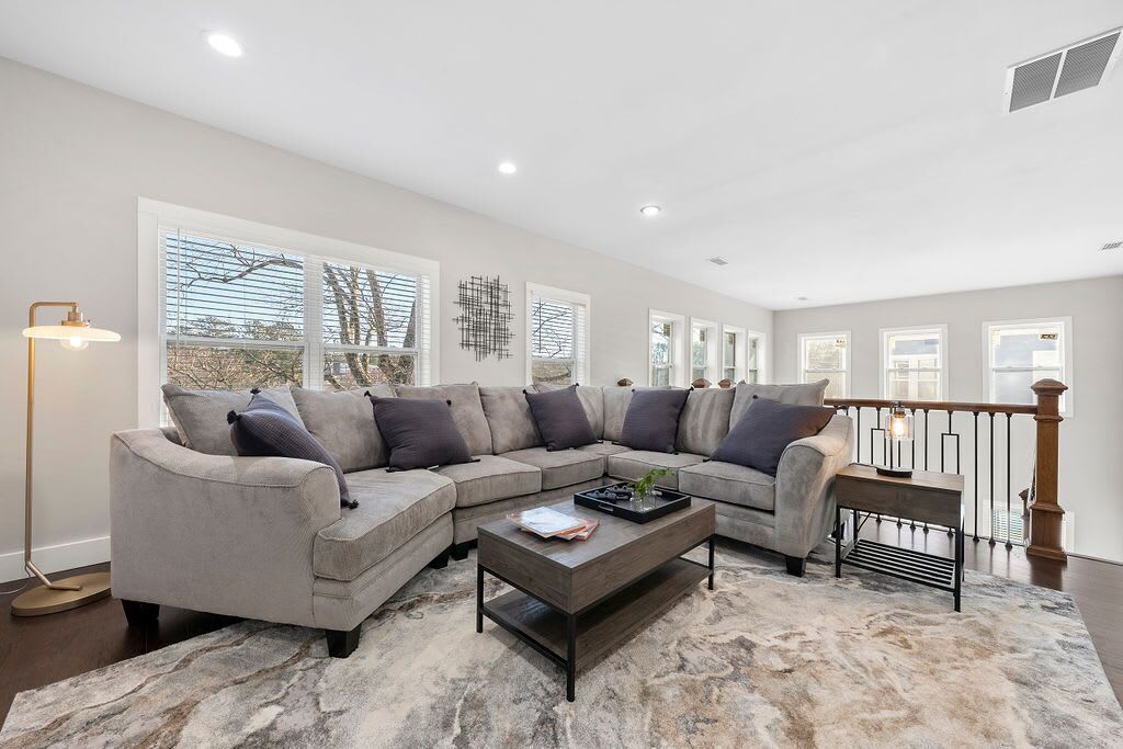 A modern living room with a sectional sofa, a coffee table, and a large window with blinds.