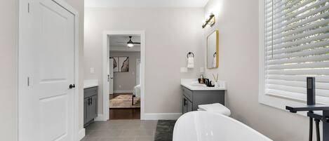 A modern bathroom with a bathtub, a vanity, and a shower area.