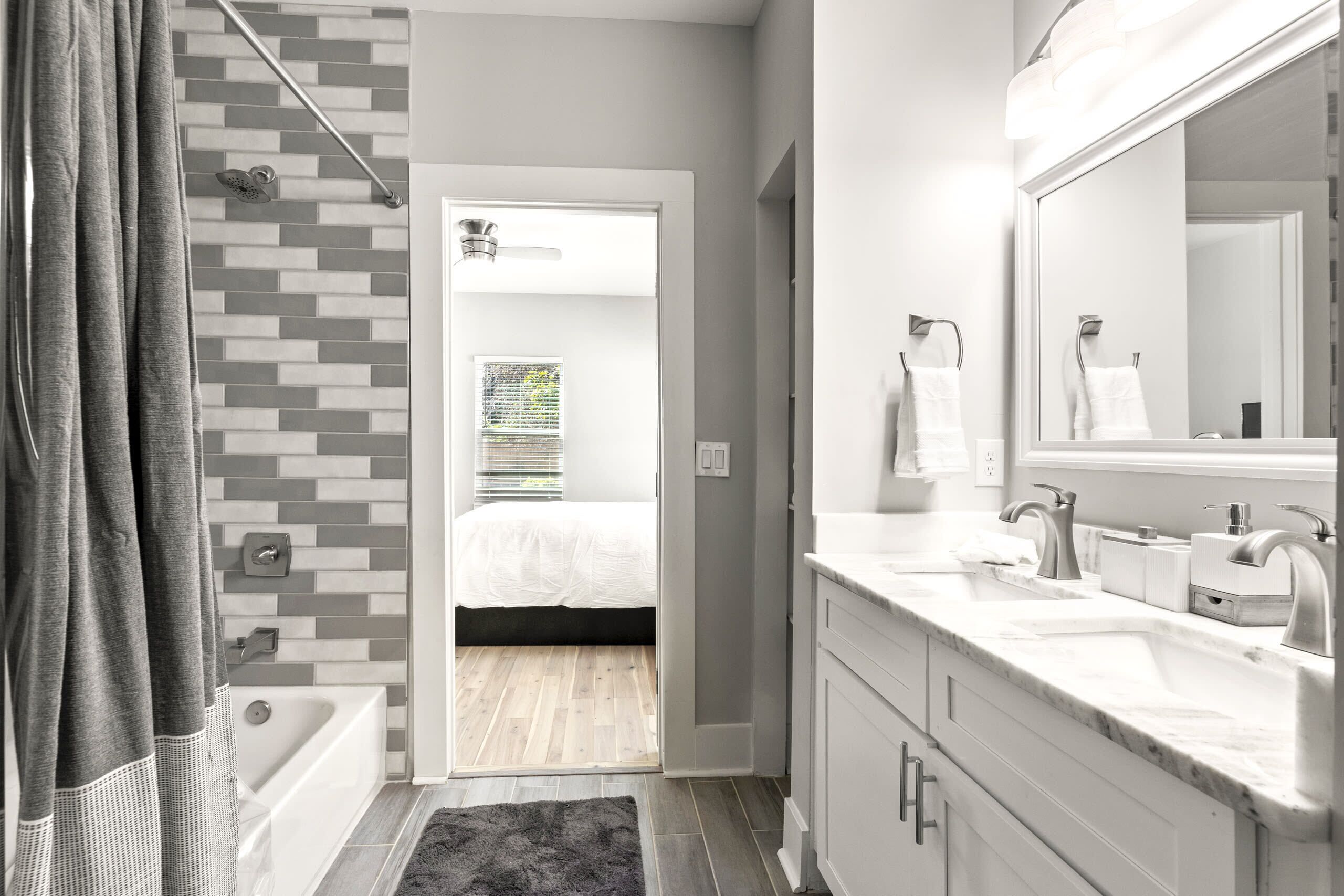 A modern bathroom with a bathtub, a shower, and a large mirror.