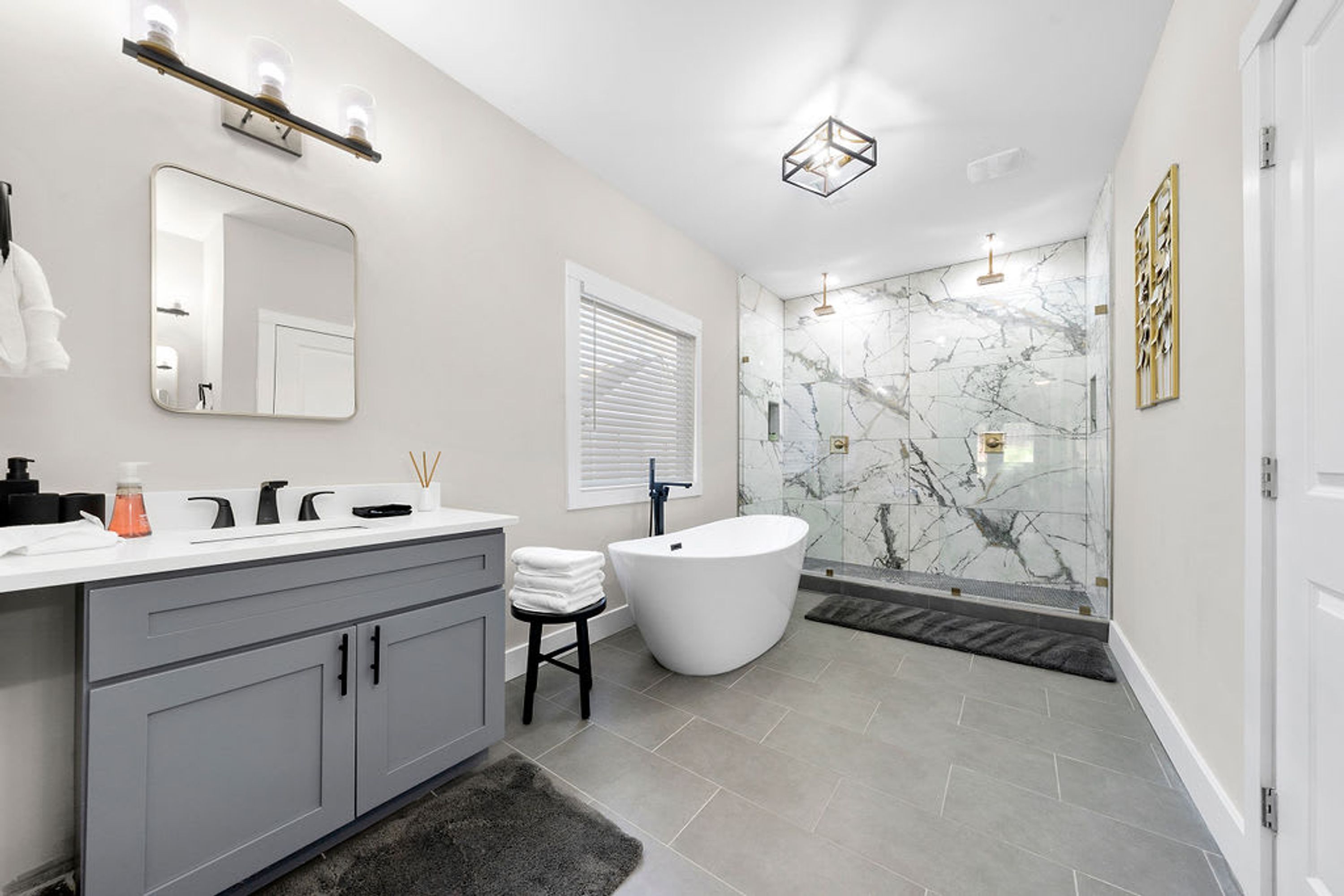 Une salle de bain moderne avec un meuble-lavabo, une baignoire sur pieds et une douche séparée par des parois en verre.