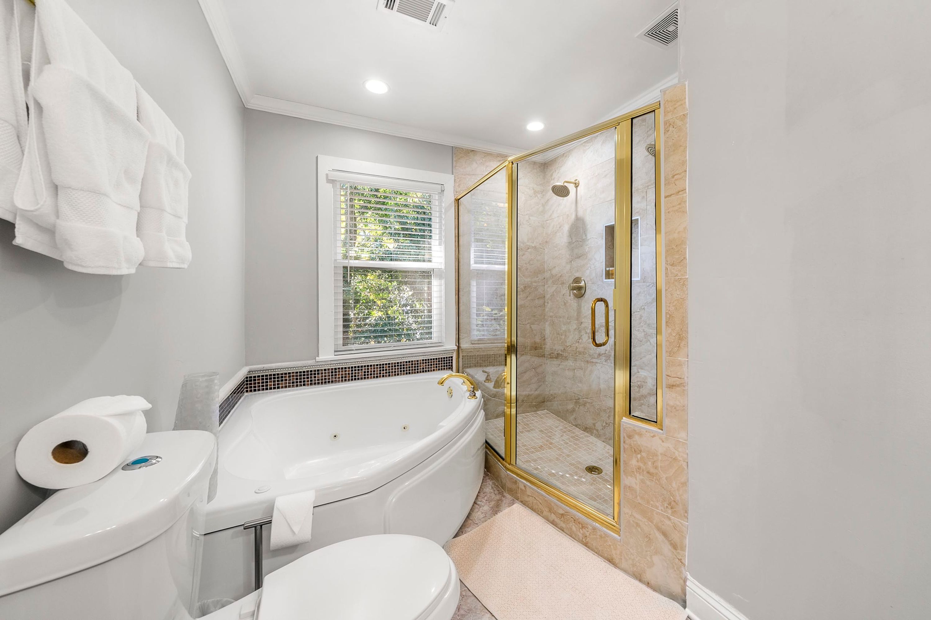A bathroom with a bathtub, toilet, and a glass-enclosed shower.