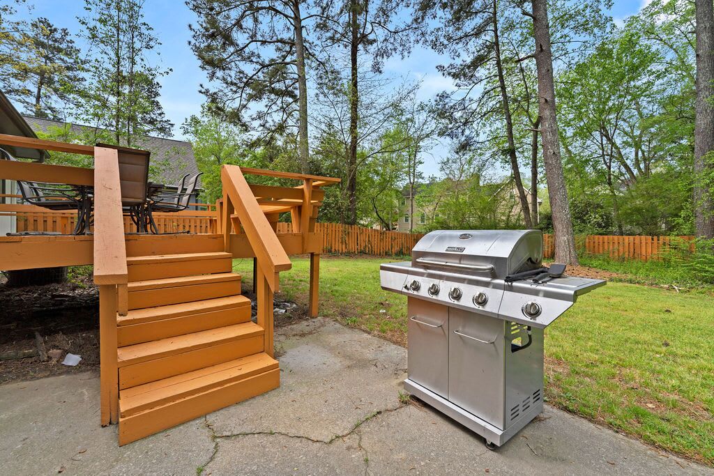 Een terras met een houten trap en een roestvrijstalen barbecue.