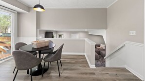 A modern kitchen with a dining area, featuring a round table with chairs, a pendant light, and a built-in island with seating. - Beautiful Newly-renovated Home in Indian Hills (Marietta)
