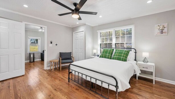 A bedroom with a bed, a ceiling fan, a window with blinds, a nightstand, and a chair. - Private 1BR Cottage In Downtown Historic Norcross (Norcross)