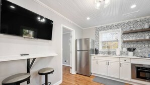 A modern kitchen with white cabinets, a stainless steel refrigerator, a built-in oven, and a black countertop. - Private 1BR Cottage In Downtown Historic Norcross (Norcross)