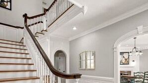 A staircase with wooden steps and white balusters, leading to a dining area with a table and chairs. - Private Resort - Lake Lanier Paradise (Gainesville)
