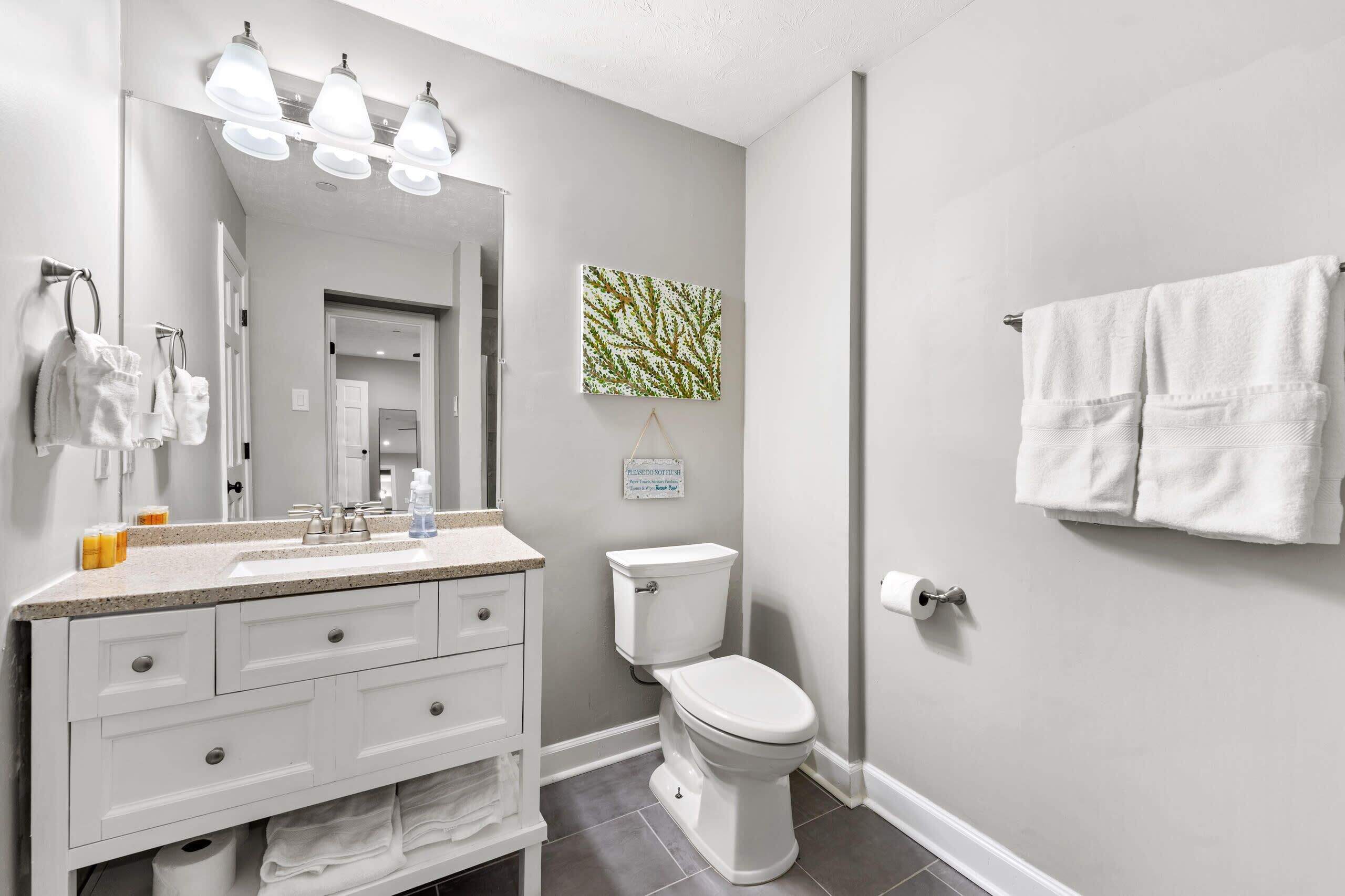 Une salle de bain avec un meuble-lavabo blanc, des toilettes et un porte-serviettes.