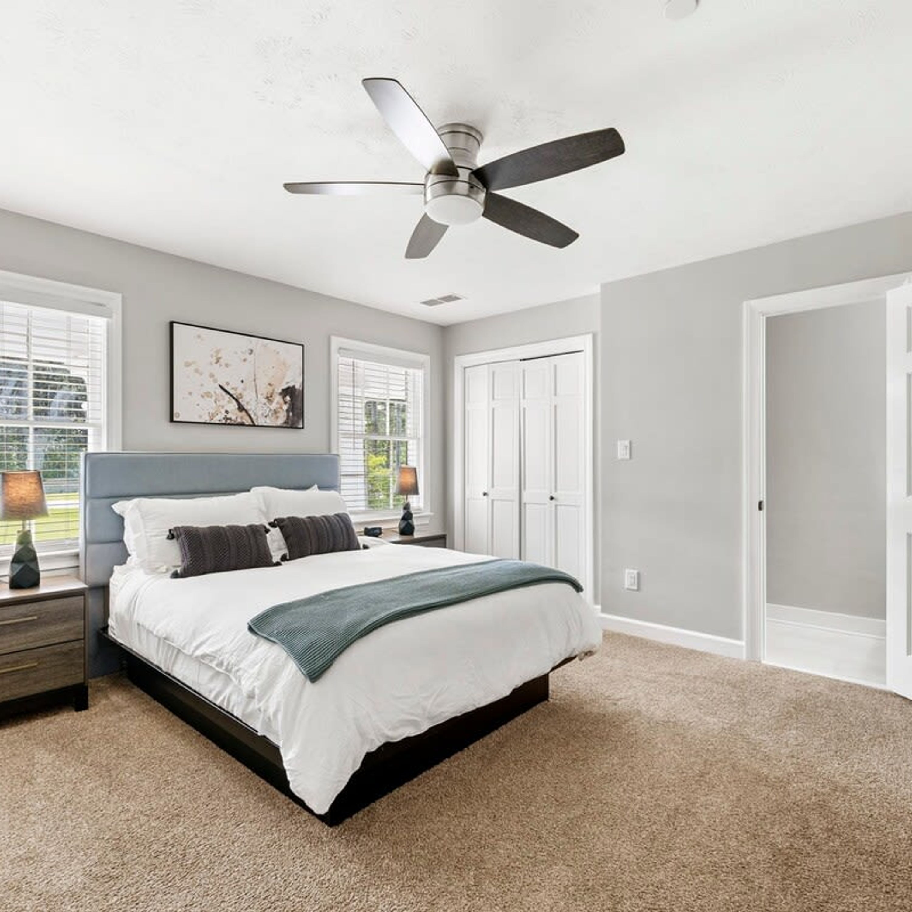 A bedroom with a bed, nightstands, a ceiling fan, and a window with blinds.