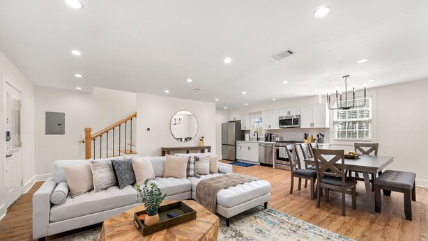 A modern living room with a sectional sofa, a wooden coffee table, and a dining area with a table and chairs. - Beautifully Modern Cottage in Historic Norcross (Norcross)